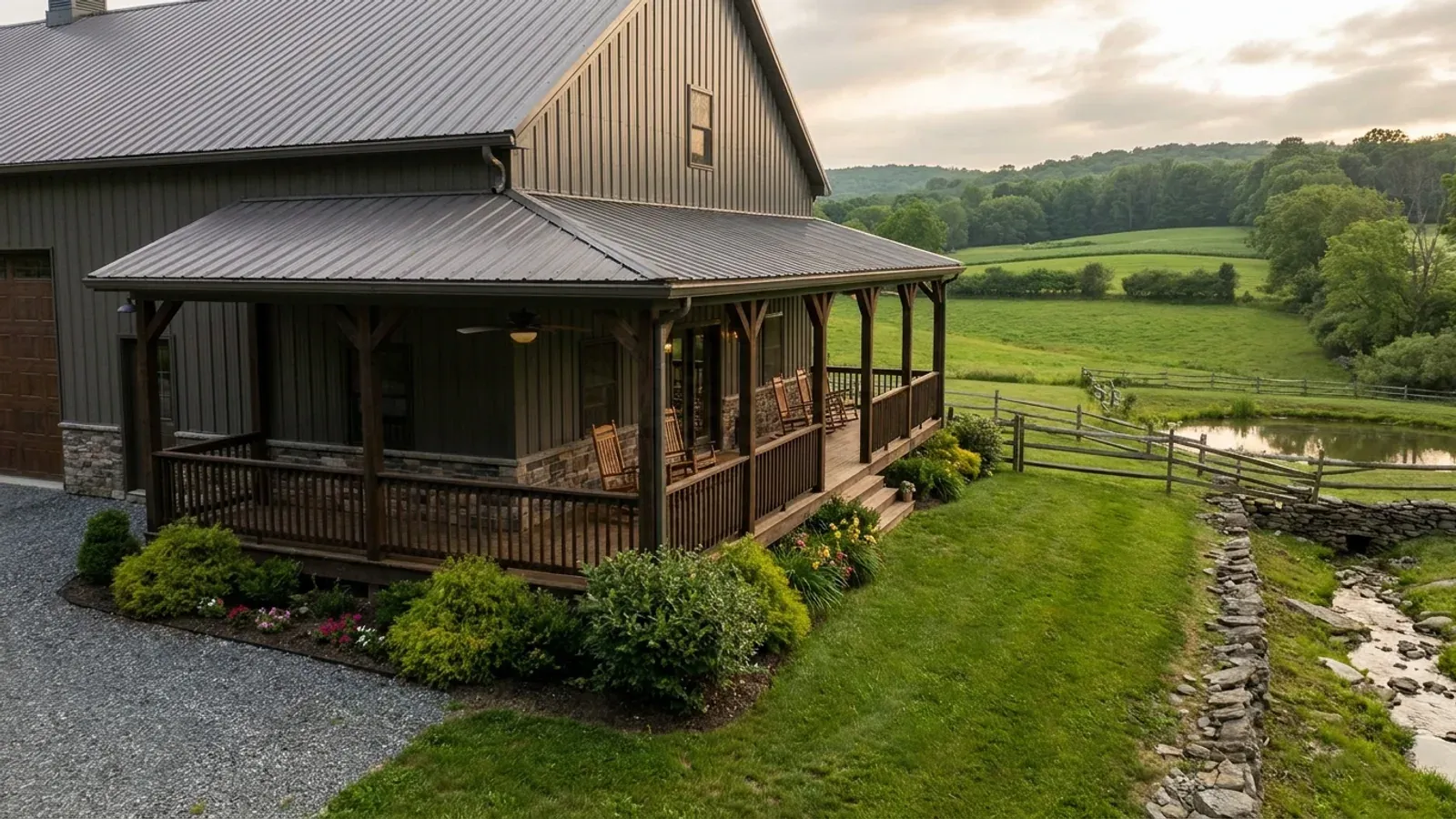 A barndominium exterior showing a deep wrap-around covered porch with posts and railing along two sides of the building.