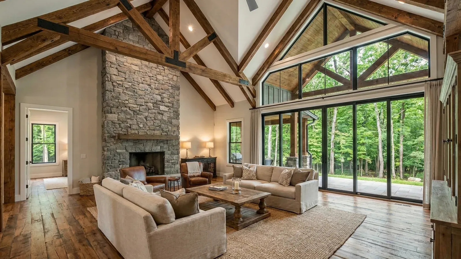 A vaulted barndominium great room with exposed wood trusses, a wall of glazed sliding doors, and a fieldstone fireplace.